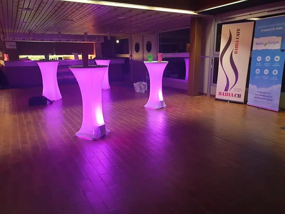 Mange-debout éclairés en rose dans un foyer, avant l’arrivée du public.
