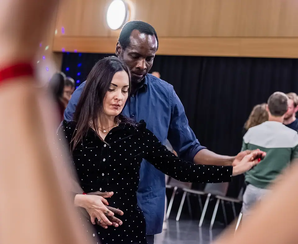 Pendant un stage, une danseuse et son partenaire : ses mains à elle posées sur la sienne à sa taille, son bras tendu dans sa main.
