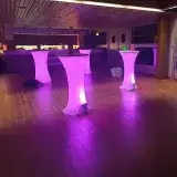 Mange-debout éclairés en rose dans un foyer, avant l'arrivée du public.