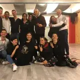 Un groupe d'amis dans une salle de danse, accroupis autour d'un t-shirt « Bailando con Villa Vida ».