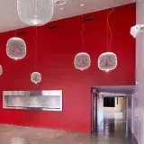 Le foyer de la salle des Utins : un grand mur rouge, des suspensions blanches en fil.